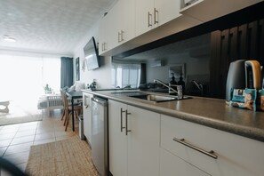 Een moderne keuken met een ingebouwde vaatwasser, een groot raam en een flatscreen televisie boven de aanrecht.