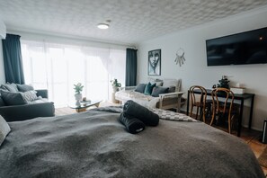 Ein modernes Schlafzimmer mit einem großen Bett, einer Couch, einem Schreibtisch und einem Fernseher.