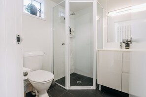 Een moderne badkamer met toilet, douchecabine en wastafel.