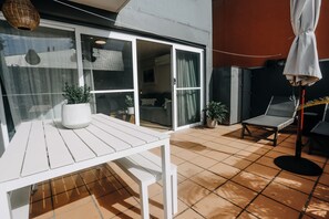 Een terras met een witte tafel, plantenpotten en een stoel.