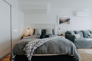 Een moderne slaapkamer met een groot bed, bedlampen, een bank en een ingelijst kunstwerk aan de muur.
