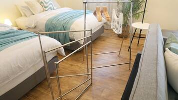 Une chambre d’hôtel avec deux lits, un canapé, une petite table et une plante.