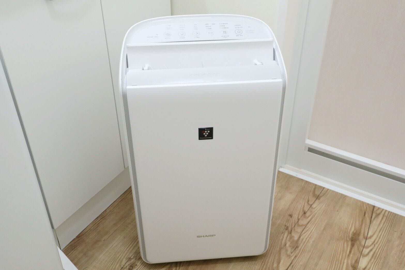 Un appareil blanc, compact et au design moderne, qui ressemble probablement à un réfrigérateur, avec un panneau de commande sur le dessus et le nom de la marque sur la façade.