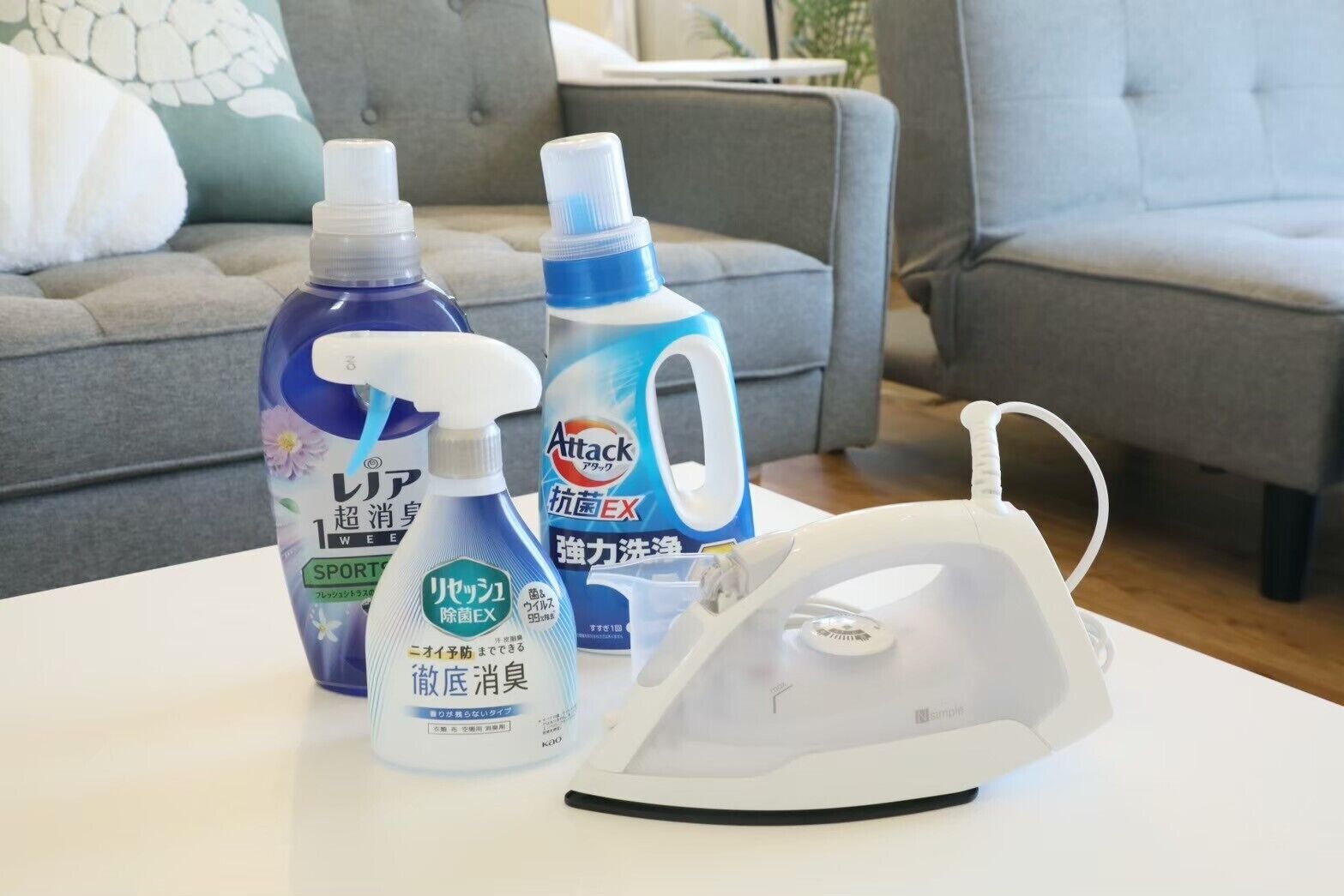 A table with cleaning products and an iron in a living room.