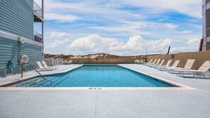 Piscina retangular com profundidade de 3,6 metros, rodeada por espreguiçadeiras e um deck de concreto.