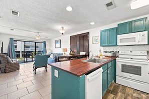 A modern kitchen with teal cabinets, a microwave, a stove, and a dishwasher. - Romar Beach 108 Blue Tides (Orange Beach)