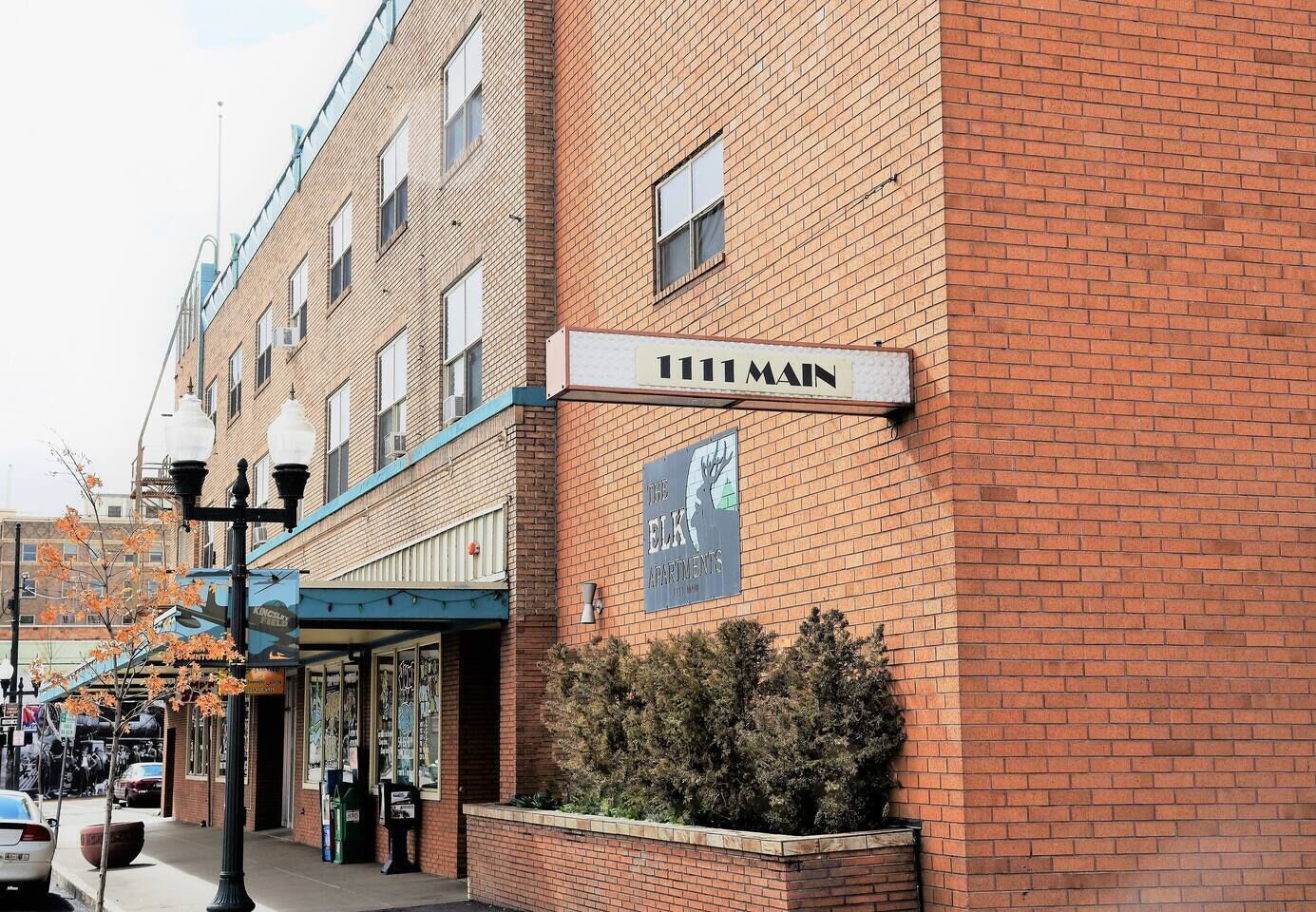 A brick building with a sign that reads '111 Main' and a sign for 'The Elk Apartments.'