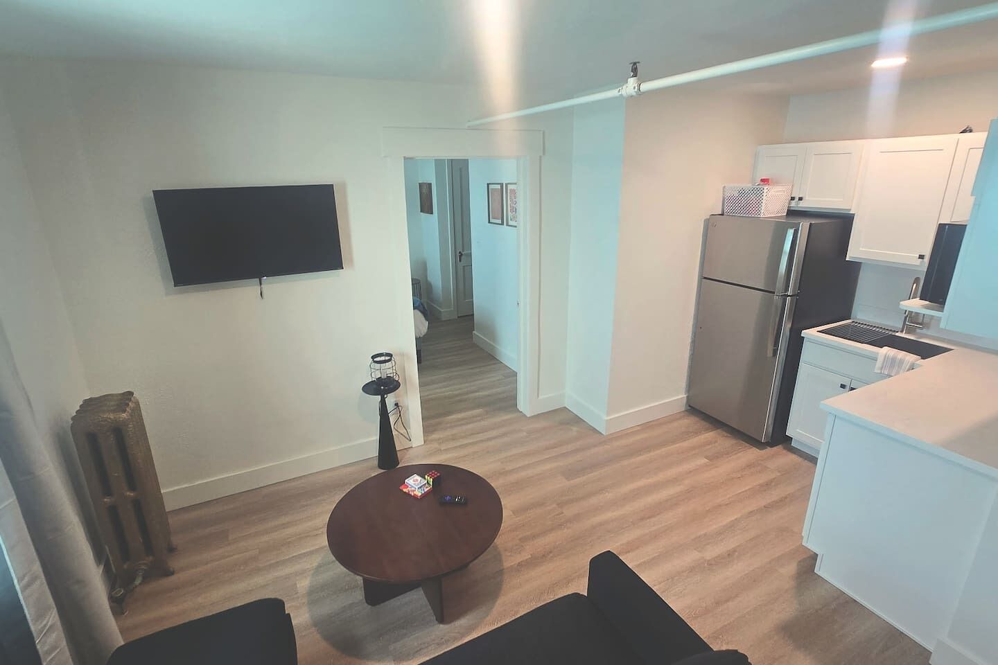 Espaço compacto com cozinha compacta, televisão de tela plana na parede, mesa redonda pequena e radiador.