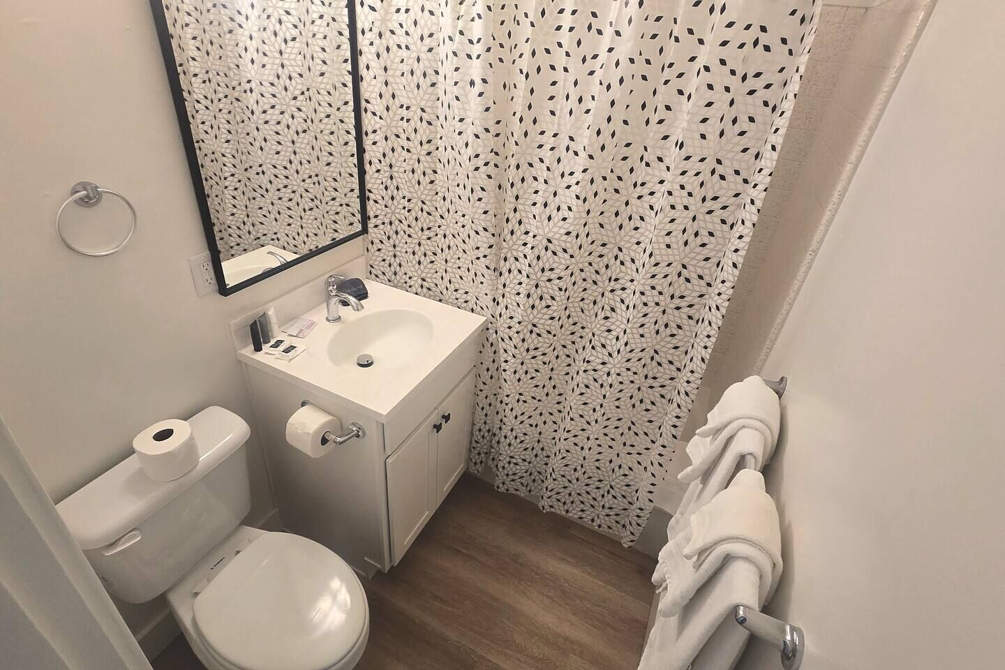 A small bathroom with a toilet, sink, and shower curtain.