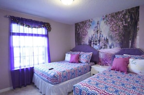 Een slaapkamer met twee bedden, paars beddengoed, een muurschildering met kasteelthema en een raam met paarse gordijnen.