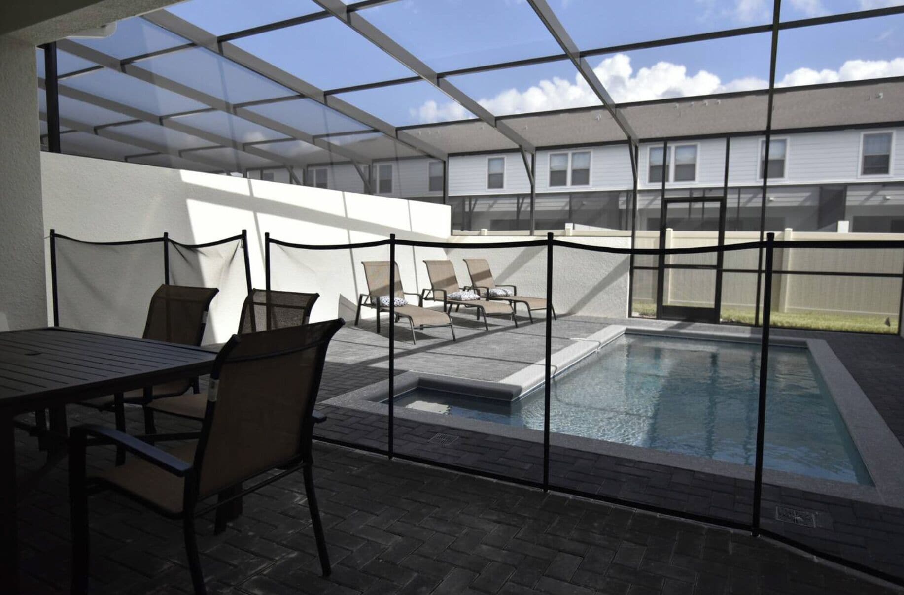 Un espace extérieur abrité comprenant une piscine, des chaises longues et une table.