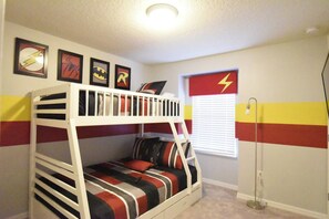 A bunk bed with a striped bedspread, framed superhero posters on the wall, and a window with blinds. - Princess/SuperHero's 5-bedroom home near Disney (Kissimmee)