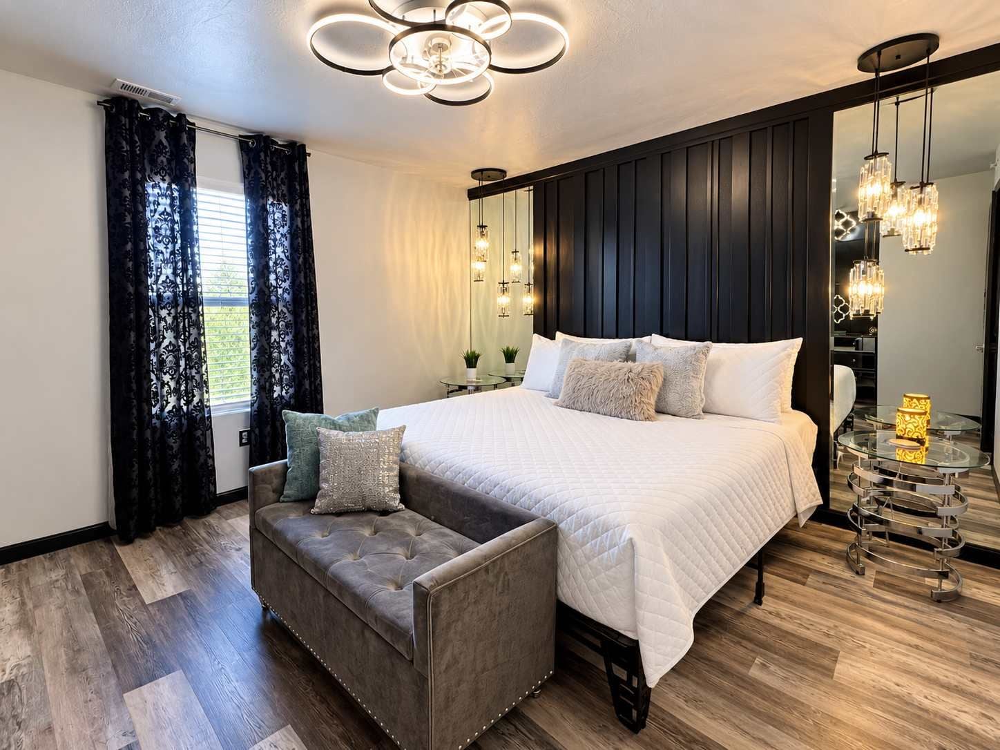 Un dormitorio con una cama grande, un sofá, una mesita de noche y un espejo.