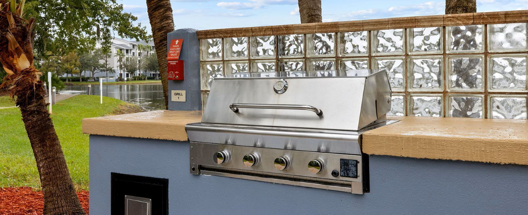 Een buitenbarbecue bevestigd aan een muur, met een betegelde spatwand.