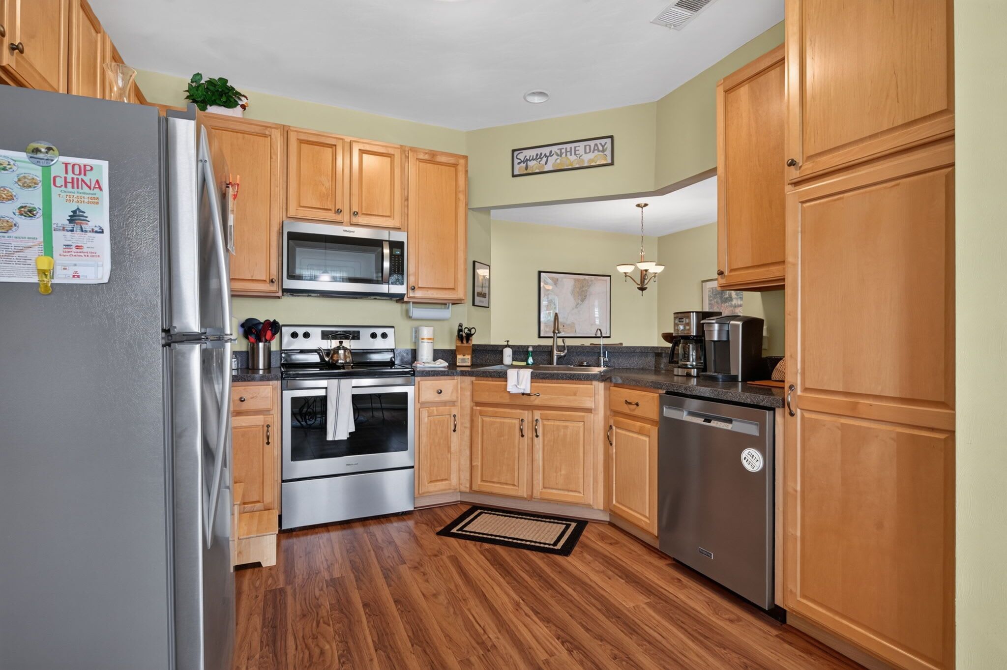 A kitchen with wooden cabinets, stainless steel appliances, and a microwave.