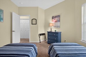 Ein Schlafzimmer mit zwei Betten, einem Schminktisch, einem Heizkörper und einer Tür zu einem Kleiderschrank.