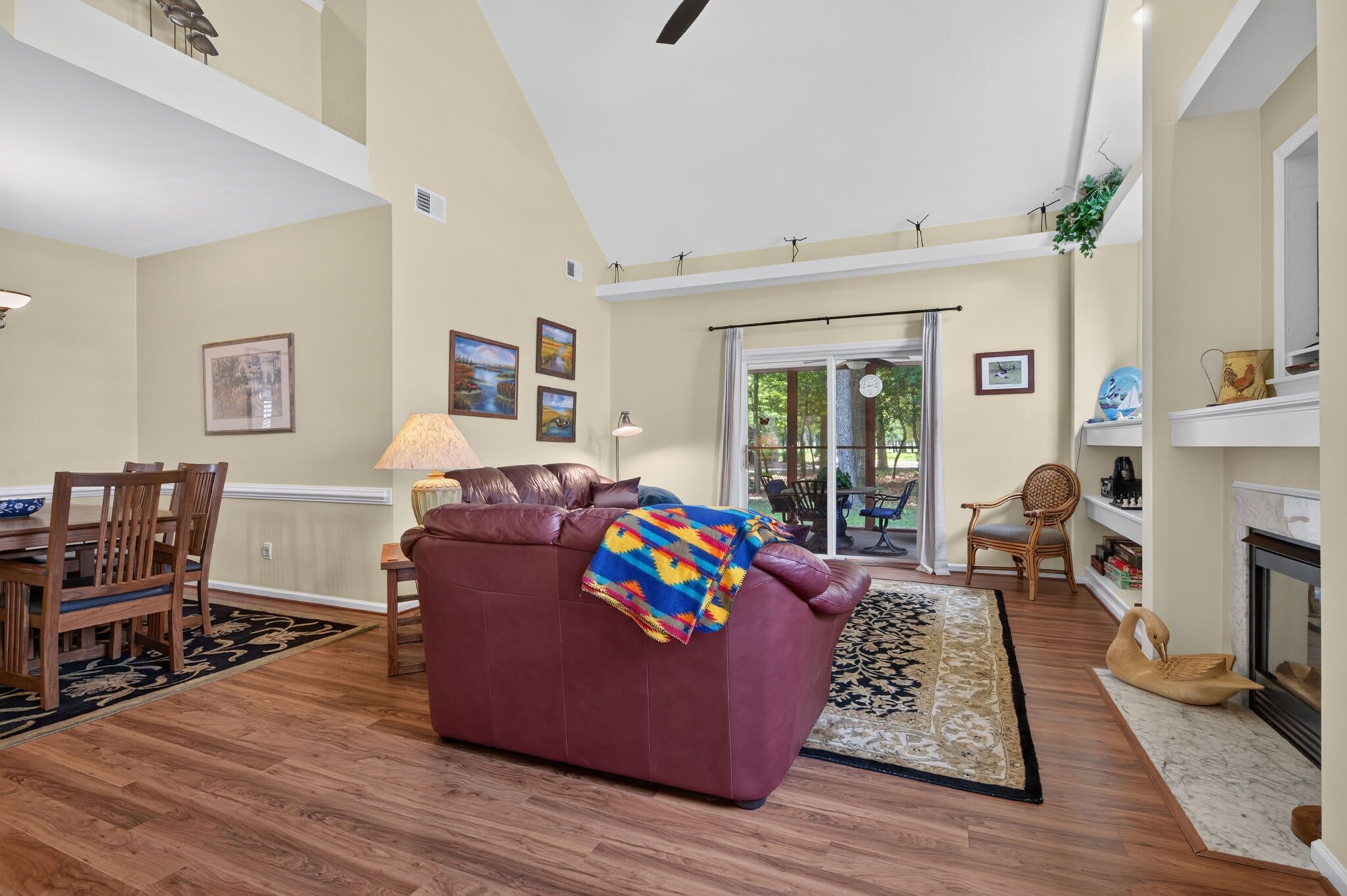 A living room with a fireplace, a dining area, and a view through a glass door to an outdoor patio.