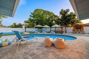 Ein Garten mit Swimmingpool, Liegestühlen und einer überdachten Sitzgelegenheit.