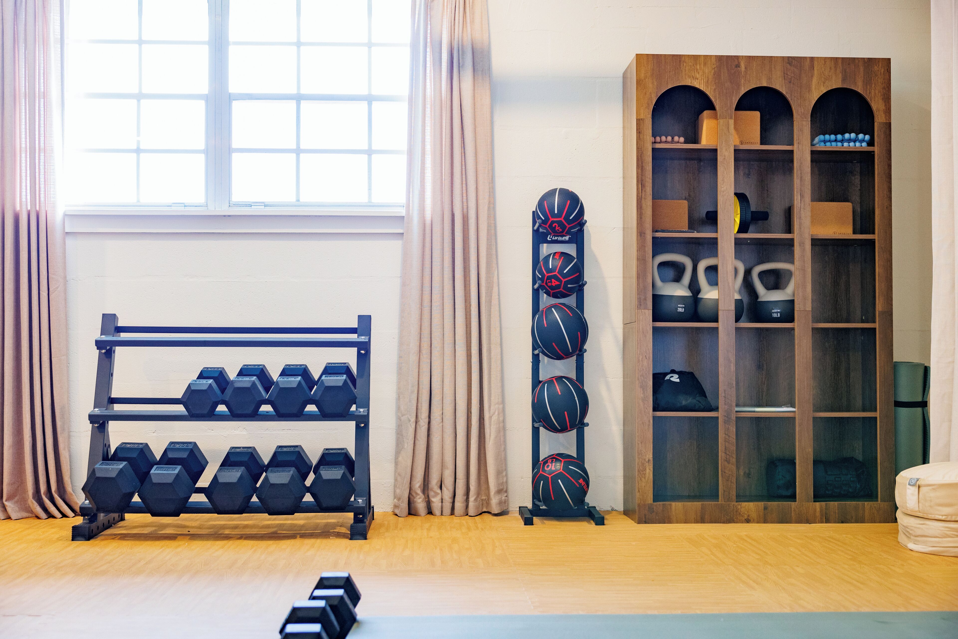 Een sportschool met gewichtsschijven, kettlebells en een rek voor gewichten.