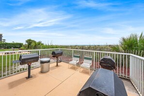 An outdoor patio with barbecue grills, a trash can, and seating. - Gulf View Condo with Shared Pool & Beach Access (Fort Walton Beach)