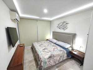 A bedroom with a bed, a desk, a chair, a TV, and an air conditioner. - Paralia Studio by WQR - Pool, Beach, 5th Avenue (Playa del Carmen)