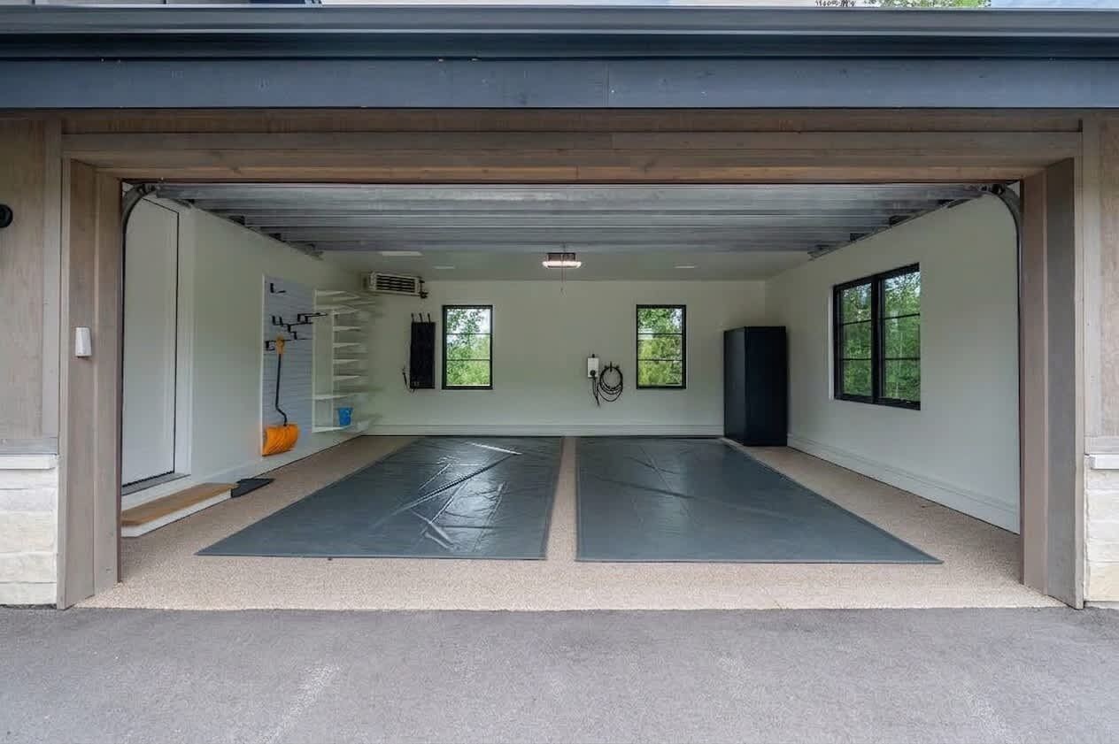 A garage with two mats on the floor, a ladder, and a speaker.