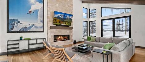 A modern living room with a fireplace, a large TV, and a sofa.
