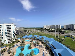 A resort with a large pool area, multiple buildings, and a view of the ocean. - Coastal Condo with Shared Pools! (Destin)