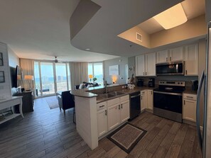 A modern kitchen with white cabinets, a stainless steel refrigerator, and a microwave. - Coastal Condo with Shared Pools! (Destin)