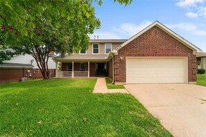 A two-story house with a front porch, a garage, and a well-maintained lawn. - 6BR Dallas Getaway - Next to Green Trails & Joe Pool Lake (Dallas)