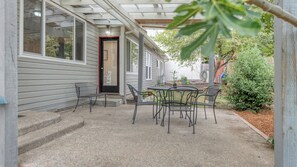 A covered patio with a table and chairs, a door, and a small garden area.