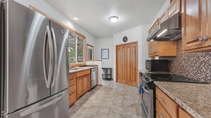 A modern kitchen with stainless steel appliances, wooden cabinets, and a tiled backsplash. - Walk-to-UO Retreat with Private Patio (Eugene)