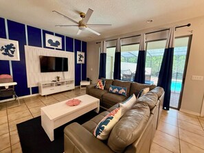 A living room with a TV, sofa, and coffee table. - [LaborDaySpecial] Mario/DisneyThemed 5Br4Ba+Pool BBQ LazyRiver (Kissimmee)