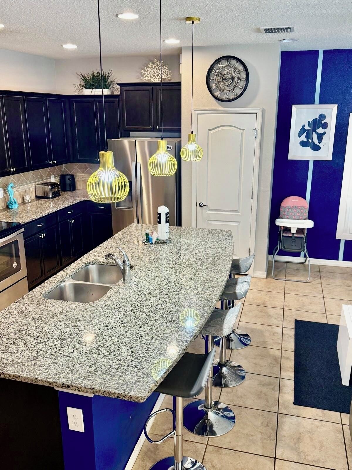 A modern kitchen with granite countertops, stainless steel appliances, and pendant lighting.