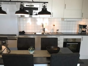 Una cocina moderna con armarios blancos, encimeras negras e iluminación colgante.