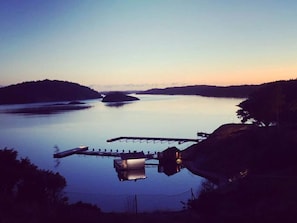 Un lago tranquilo con un muelle que se adentra en el agua, rodeado de colinas.
