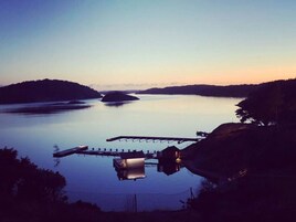 Un lago tranquilo con un muelle que se adentra en el agua, rodeado de colinas.