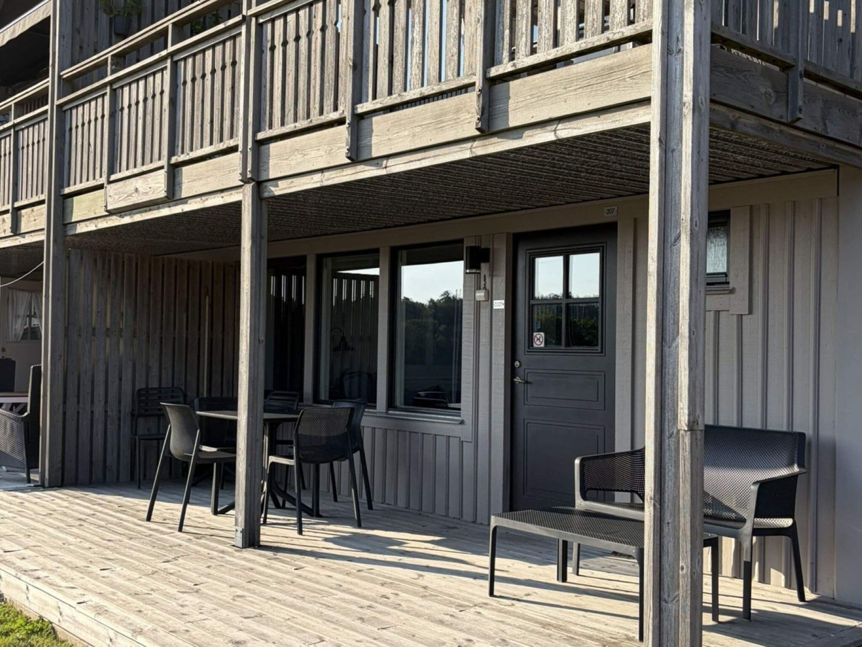 A wooden deck with outdoor seating, a covered area, and a door with a window.