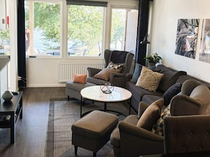 Una sala de estar con sofá, sillones, una mesa de centro y vistas al exterior.