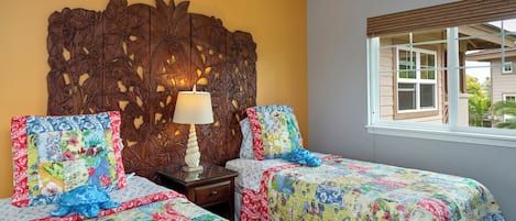 Una habitación con dos camas, un cabecero de madera, una mesita de noche con lámpara y una ventana con persianas.