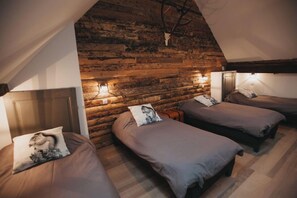 Ein Zimmer mit vier nebeneinander stehenden Betten, Holzwänden und einer geneigten Decke.