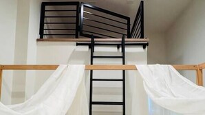 A bunk bed with a ladder, white bedding, and sheer curtains. - Delightful Studio apartment with AC in Seattle (Seattle)