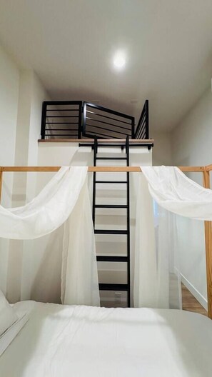 A bunk bed with a ladder, white bedding, and sheer curtains. - Delightful Studio apartment with AC in Seattle (Seattle)