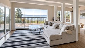 A spacious living room with a large sliding glass door leading to a deck, a sofa, a coffee table, and a view of the outdoors. - Delightful Studio apartment with AC in Seattle (Seattle)