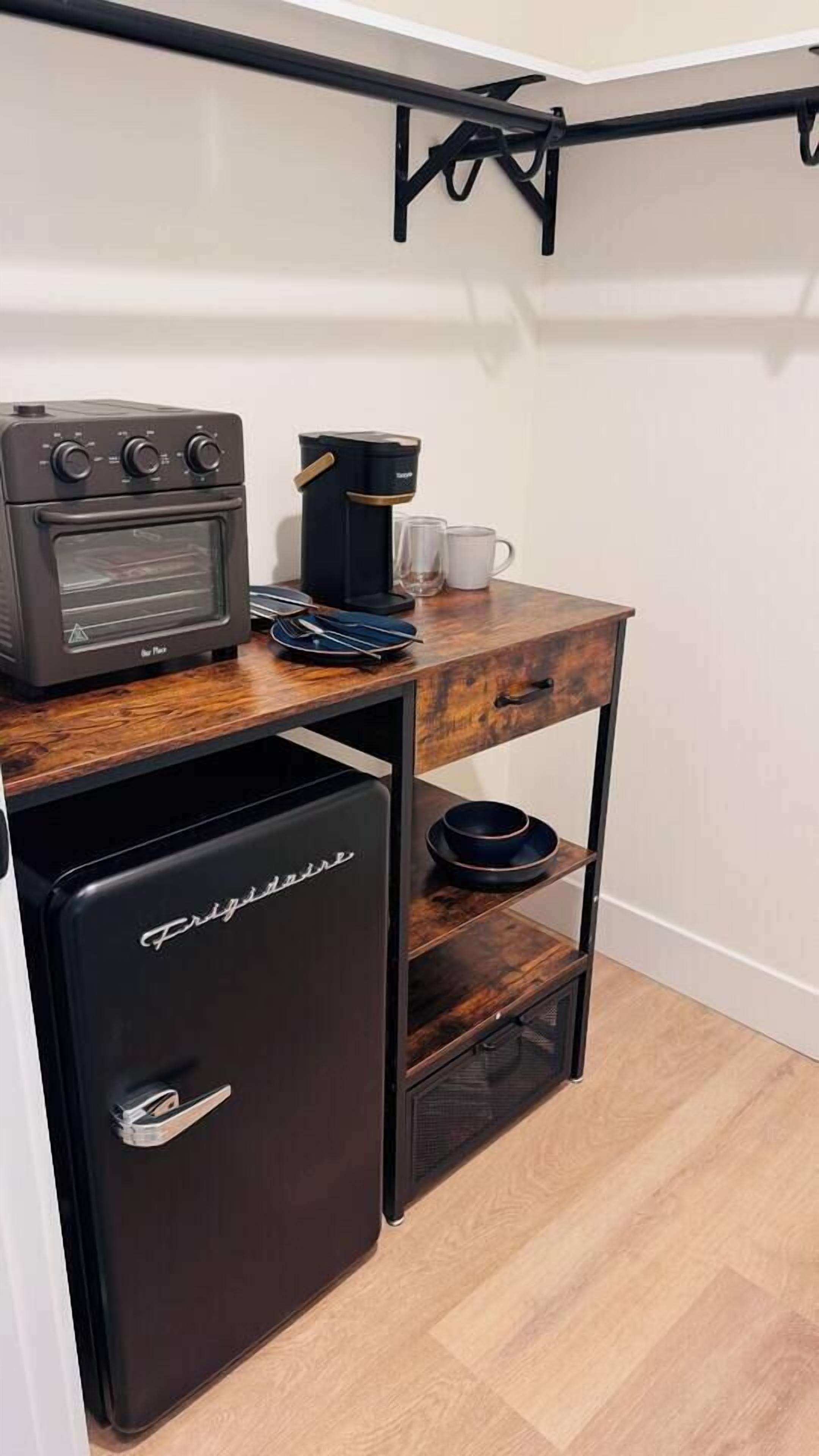 Eine kompakte Küchenzeile mit Kaffeemaschine, Toaster und kleinem Kühlschrank.