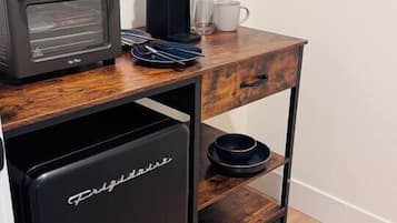 Eine kompakte Küchenzeile mit Kaffeemaschine, Toaster und kleinem Kühlschrank.