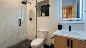 A modern bathroom with a glass-enclosed shower, a toilet, and a vanity with a mirror. - Delightful Studio apartment with AC in Seattle (Seattle)