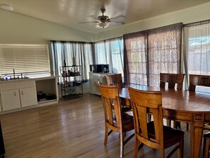 Un comedor con una mesa y sillas de madera, una cocina con pileta y alacenas, y un ventilador de techo.