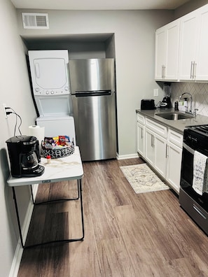 A compact kitchen with a stainless steel refrigerator, a coffee maker, and a toaster on the counter.