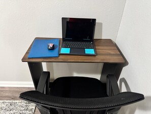 Een laptop op een houten bureau met een blauwe map en een muis.